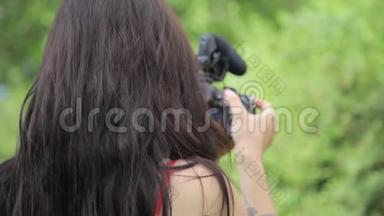 年轻的混血女独立电影制作人在绿色的自然环境中拍摄背景草